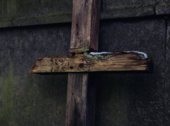 a broken wooden crucifix leaning on concrete